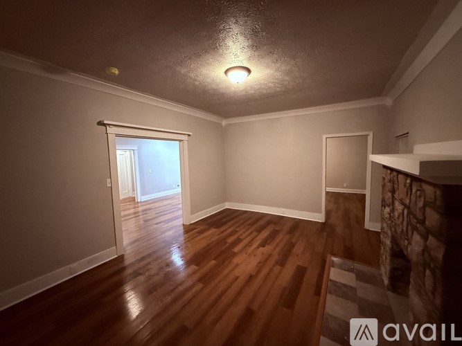 A room with wooden flooring and a door in the background.