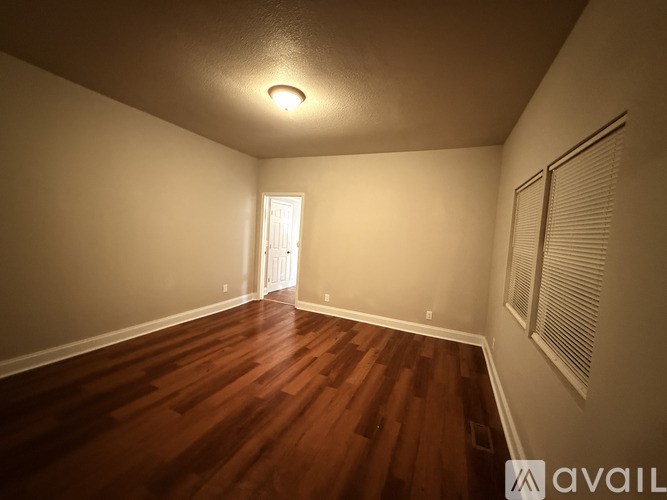 A room with wooden floors and two windows.