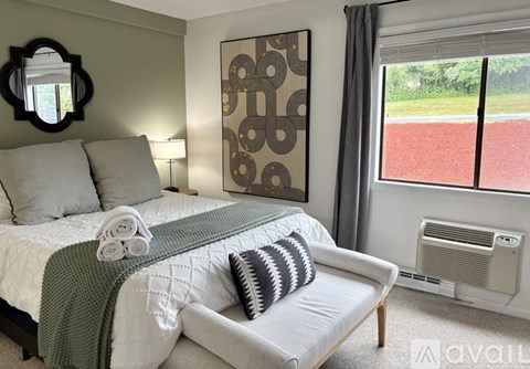 A bedroom with a bed, a couch, and a window overlooking a red area.