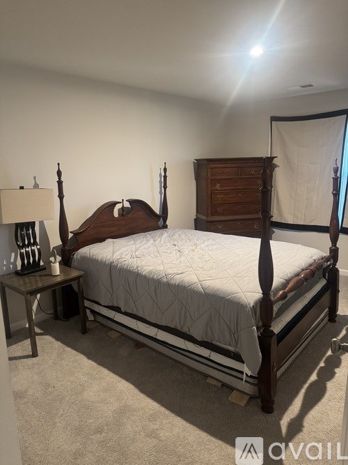 A bedroom with a bed, nightstand, and lamp.