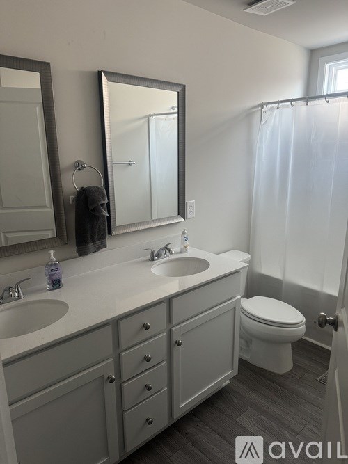 A bathroom with a toilet, sink, and mirror.
