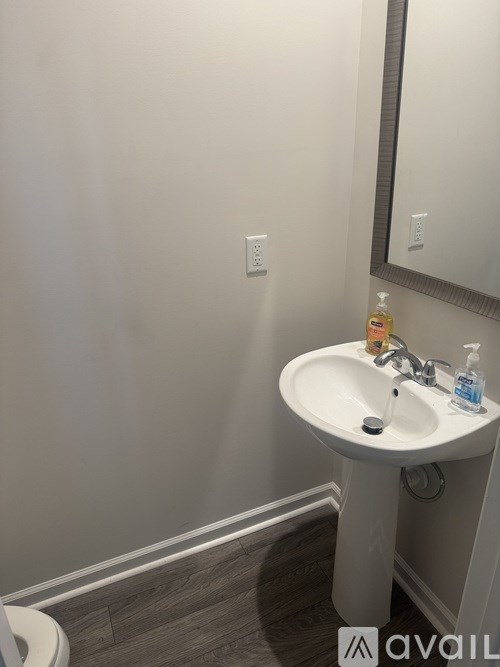 A white pedestal sink with a mirror above it.