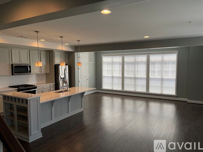 A spacious kitchen with dark wood floors and grey cabinets.