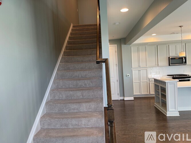 A staircase with a wooden handrail leads to a kitchen area.