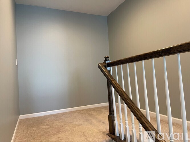 A room with a carpeted floor and a wooden staircase.