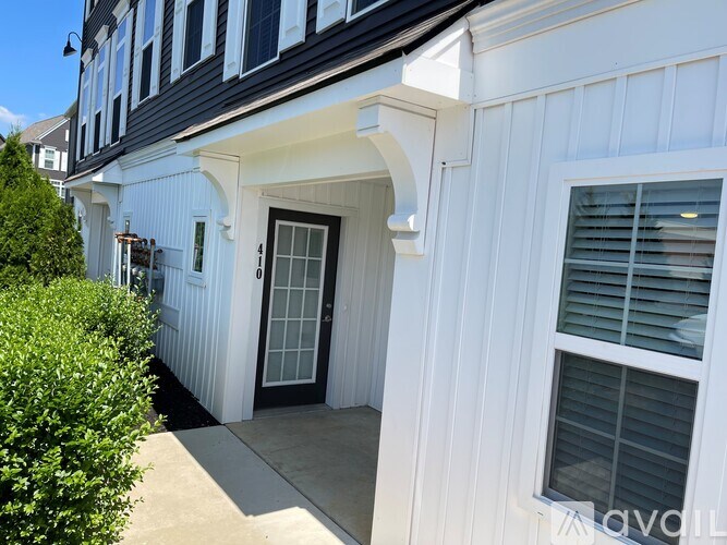 A white house with a black door and a window with blinds.