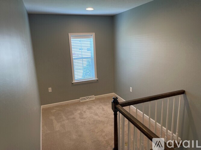 A room with a window and a carpeted floor.