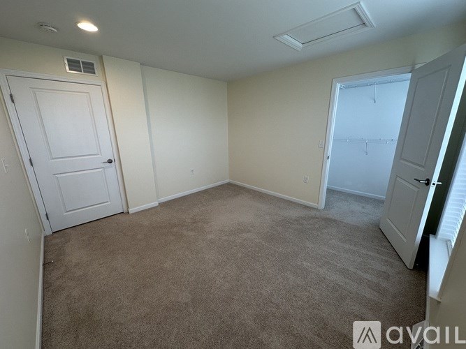 A white closet with a door open to a room with a window.