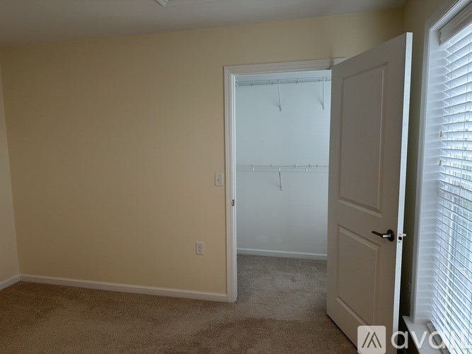 A white closet with a white door and white shelves.