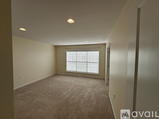 A room with pink walls, a white door, and a window with blinds.