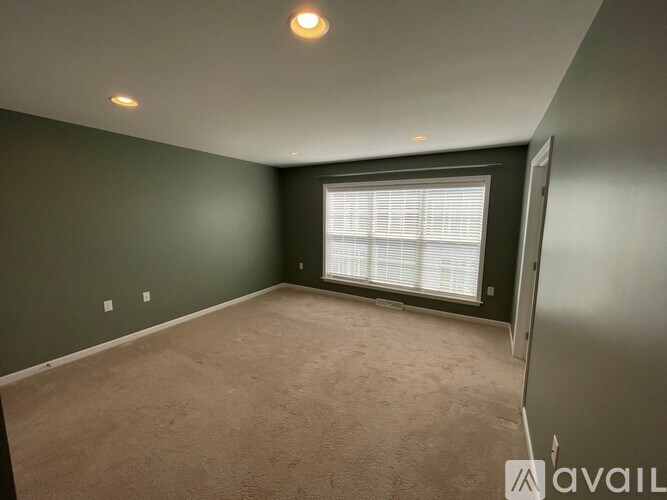 A room with a window covered by blinds and carpeted floor.
