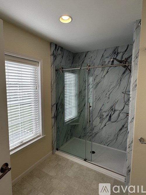 A white door is open to a room with a white wall and a white shelf.