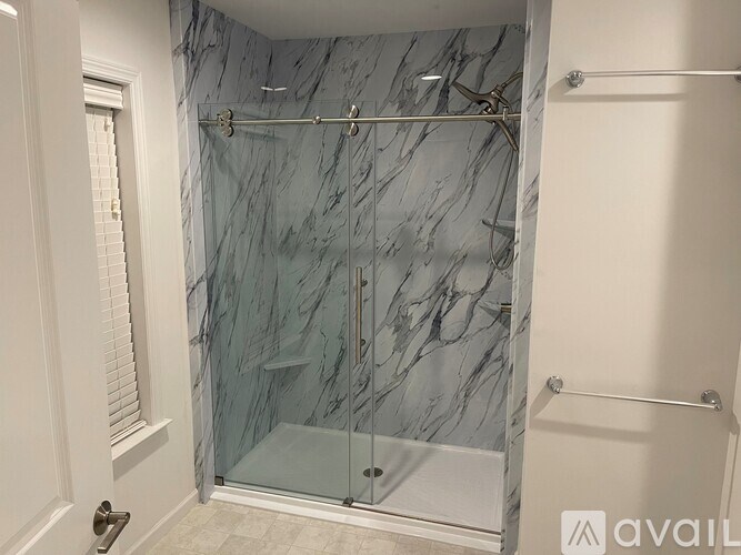 A bathroom with a marble wall and a glass shower door.