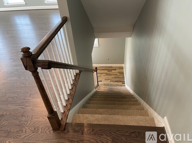 A staircase with a wooden handrail and beige carpeted steps.
