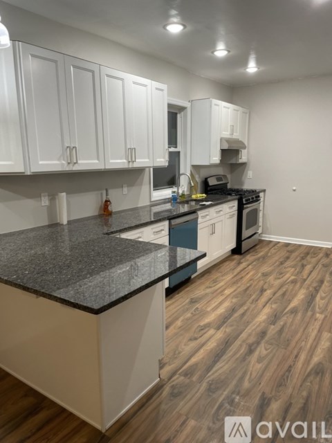 A kitchen with white cabinets and a granite countertop.