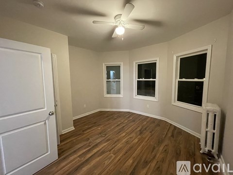 A room with a white door, two windows, and a ceiling fan.