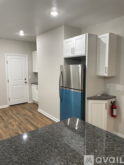 A kitchen with a granite counter top and a stainless steel refrigerator.