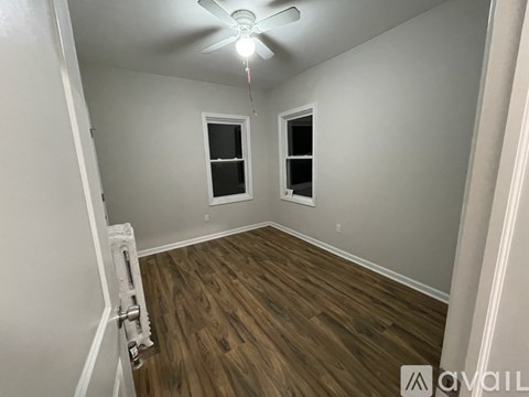 A room with a ceiling fan and two windows.