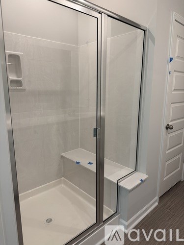 A shower stall with a glass door and a white door next to it.
