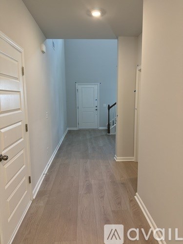 A hallway with a door on the left and a staircase on the right.