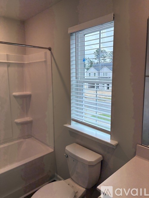 A white toilet sits next to a window in a bathroom.