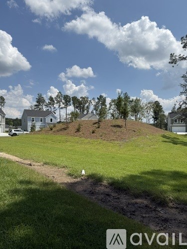 A grassy hill with a white cone in the foreground and houses in the background.