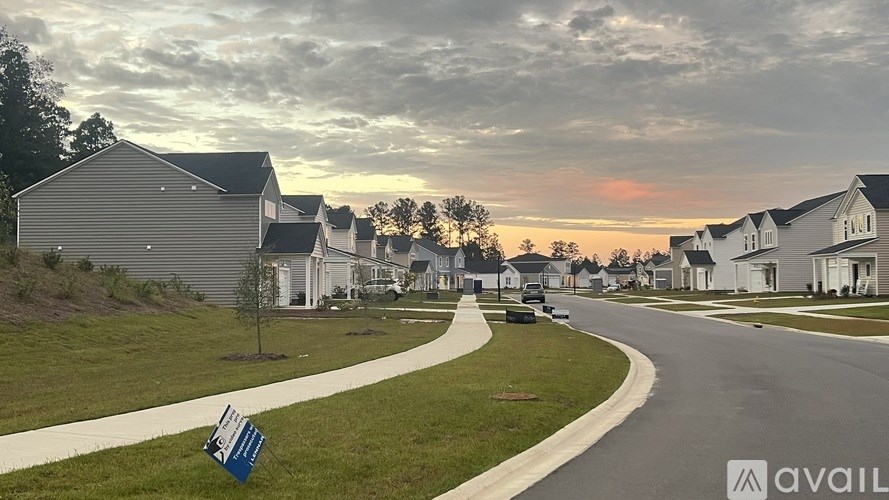A suburban street with houses and a sign that says "available".