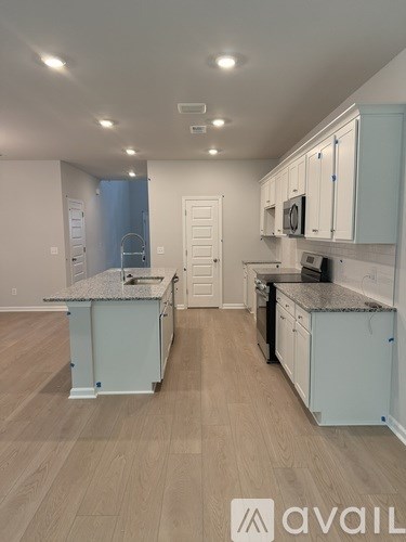 A kitchen with light wood floors and white cabinets.