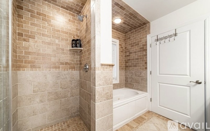 A bathroom with a white door and a tiled shower area.