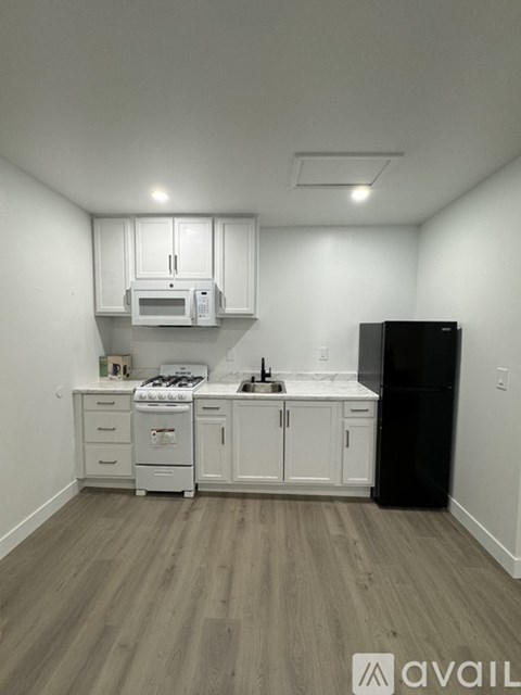 A kitchen with white cabinets and a black refrigerator.