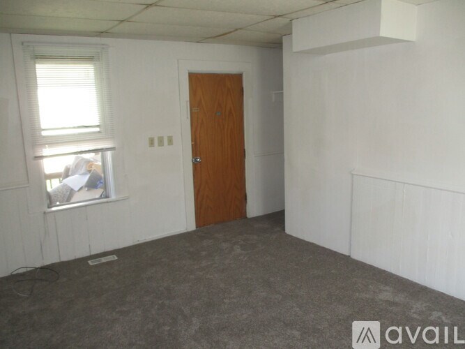 A room with a brown door and a window with blinds.