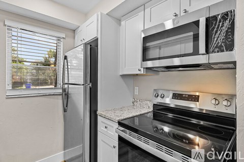 A kitchen with a stainless steel refrigerator, microwave, and oven.