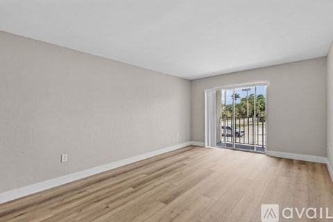 A room with wooden flooring and a window overlooking a parking lot.