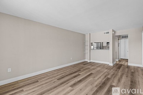 A spacious room with wooden flooring and white walls.