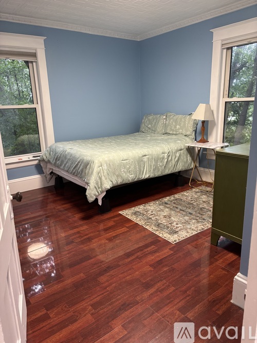 A bedroom with a bed, desk, and window.