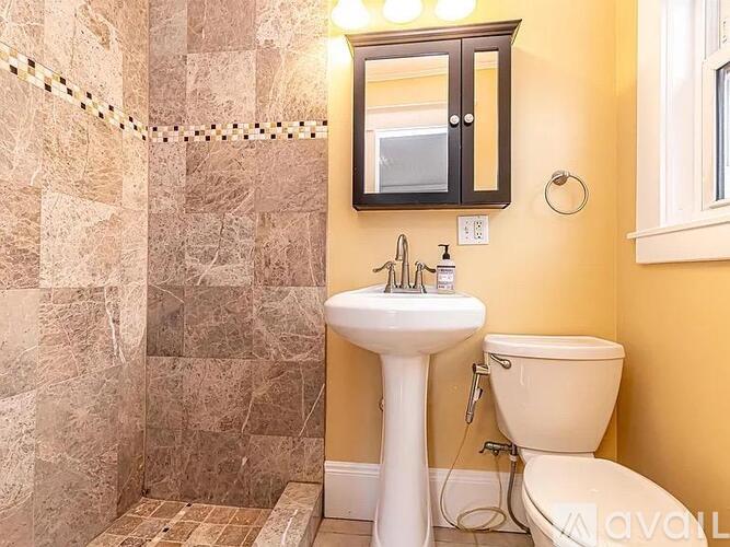 A bathroom with a sink, toilet, and a shower with a tiled wall.