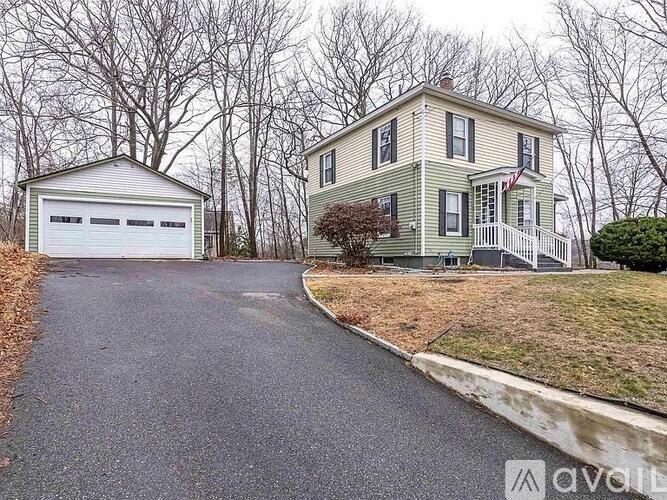A two-story house with a garage is situated in a quiet neighborhood.