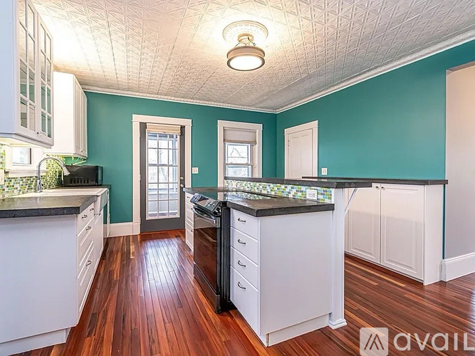 A kitchen with white cabinets and a black countertop.