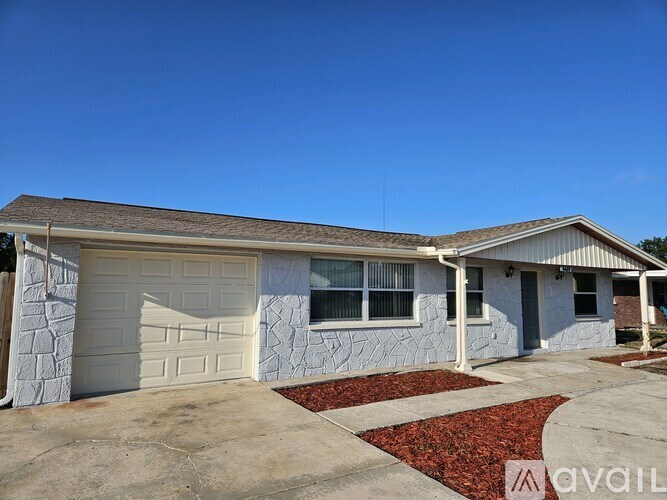 A house with a white garage door and a stone wall.