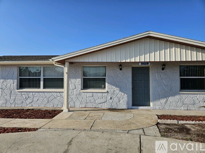 A house with a white stone exterior and a grey door.