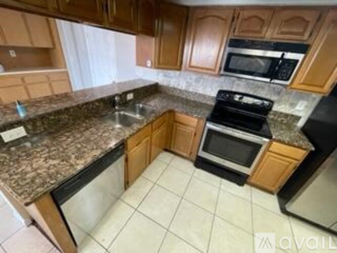A kitchen with granite countertops and wooden cabinets.