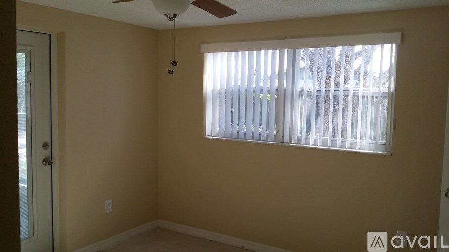 A room with a window covered by white blinds and a ceiling fan.