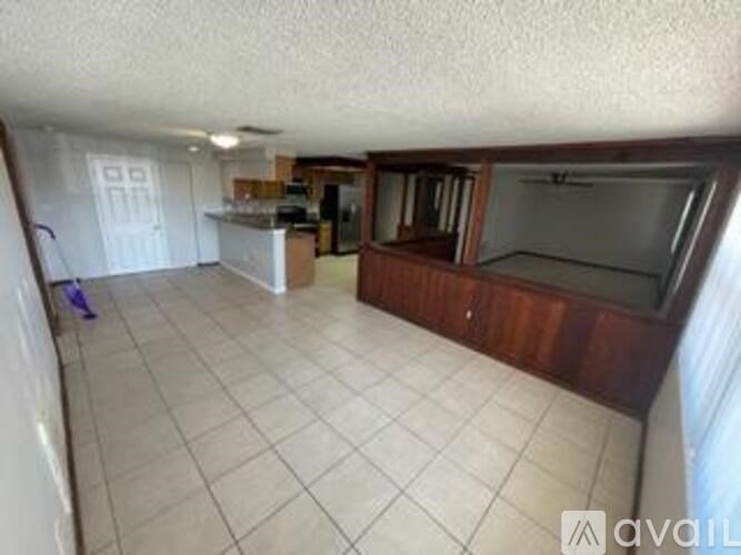 A living room with a white tile floor and a wooden entertainment center.