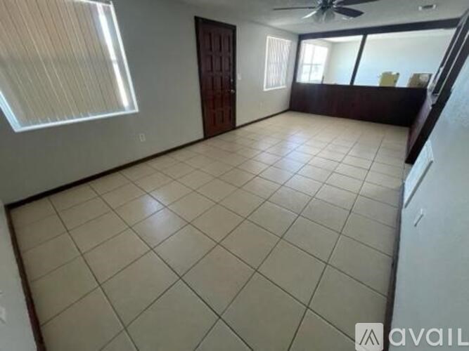 A spacious room with a ceiling fan and tiled flooring.