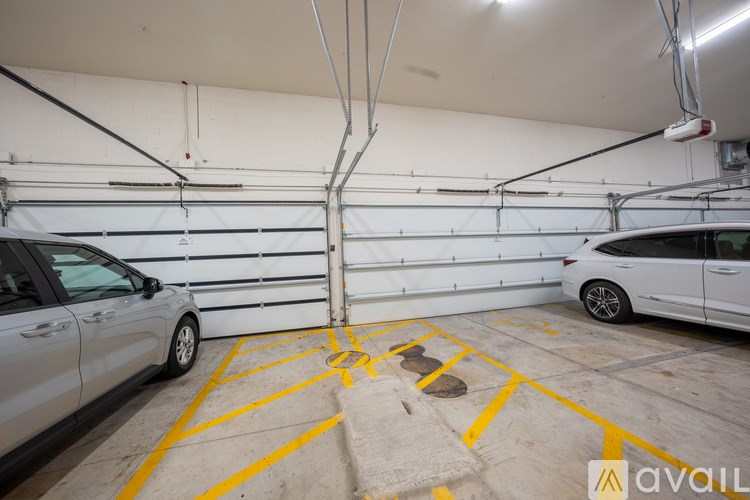 Two cars are parked in a garage with yellow lines on the floor.