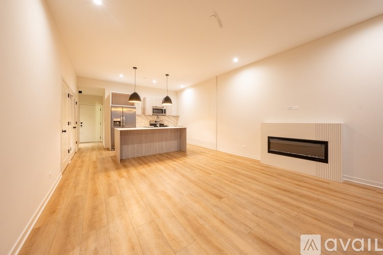 A spacious room with wooden flooring and a fireplace.