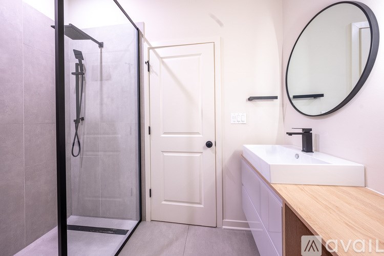 A bathroom with a white sink and a round mirror.