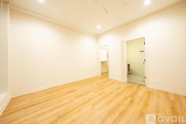 A room with wooden flooring and a door on the right side.
