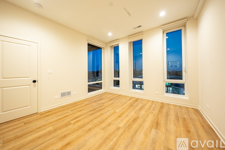 A room with wooden floors and three windows.