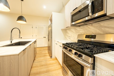 A modern kitchen with a stove, sink, and microwave.